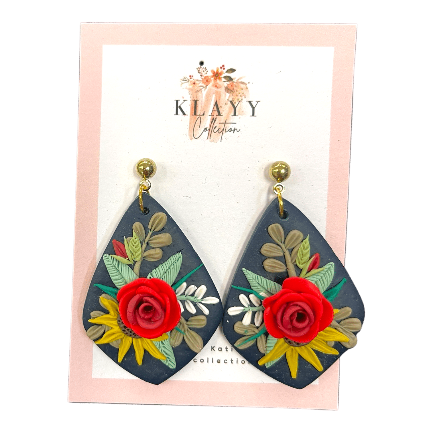 Midnight Rose earrings showcase a red rose on navy clay with rich green foliage and golden studs. Handmade floral elegance.