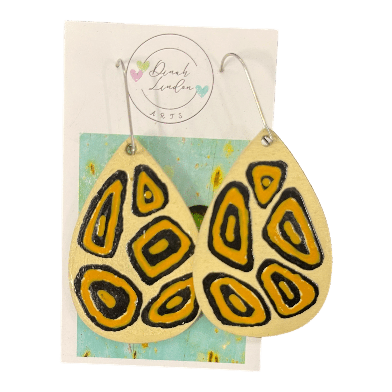 Savannah Signal Drops – golden tribal-style teardrop earrings with bold black shapes on a cream background.