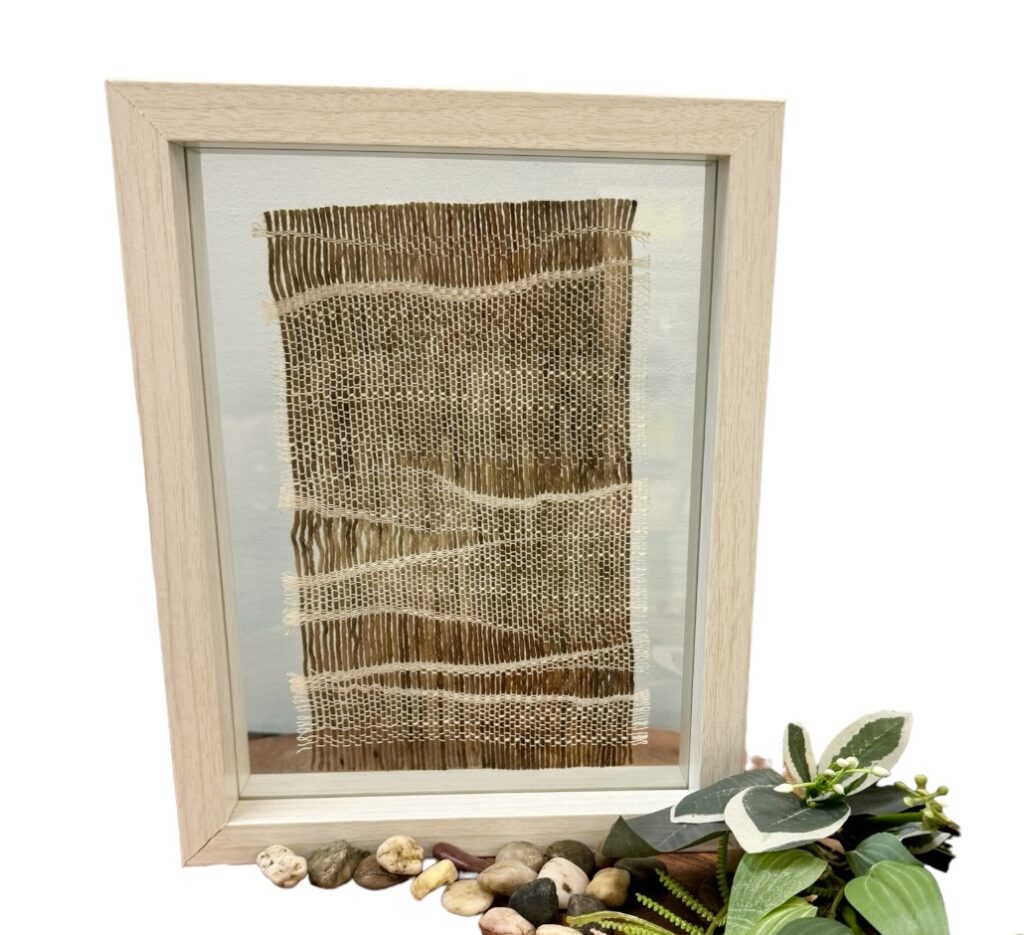 Explore "Sunset Plains" by Ashculme Textiles, a stunning artwork made from hand-reared alpaca wool and silk, dyed with natural bush leaves. This piece captures the warm beauty of the Australian plains at sunset, framed between glass panels for a detailed display.