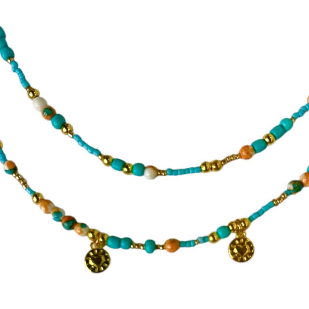 The Mediterranean Charm Necklace by Art In Stone Jewellery features turquoise, coral beads, and gold-plated coins, inspired by the coastal Mediterranean.