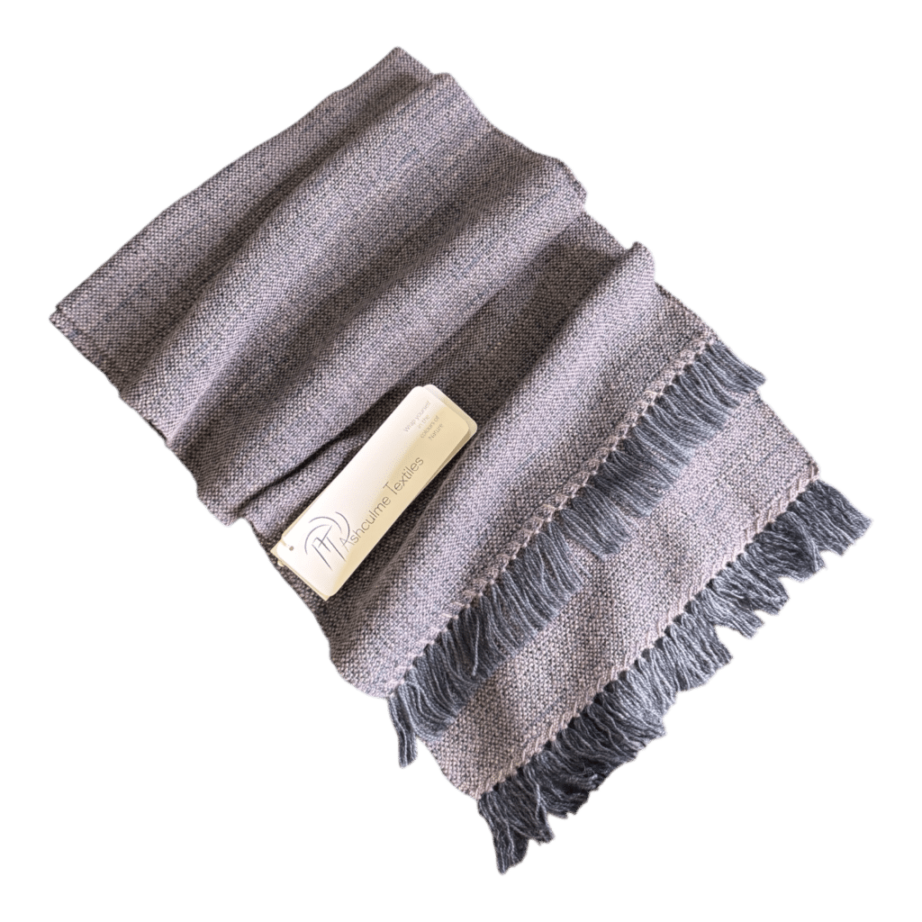 Charcoal and blush-toned handwoven scarf in merino and alpaca, finished with grey fringe. Naturally dyed and timelessly elegant.
