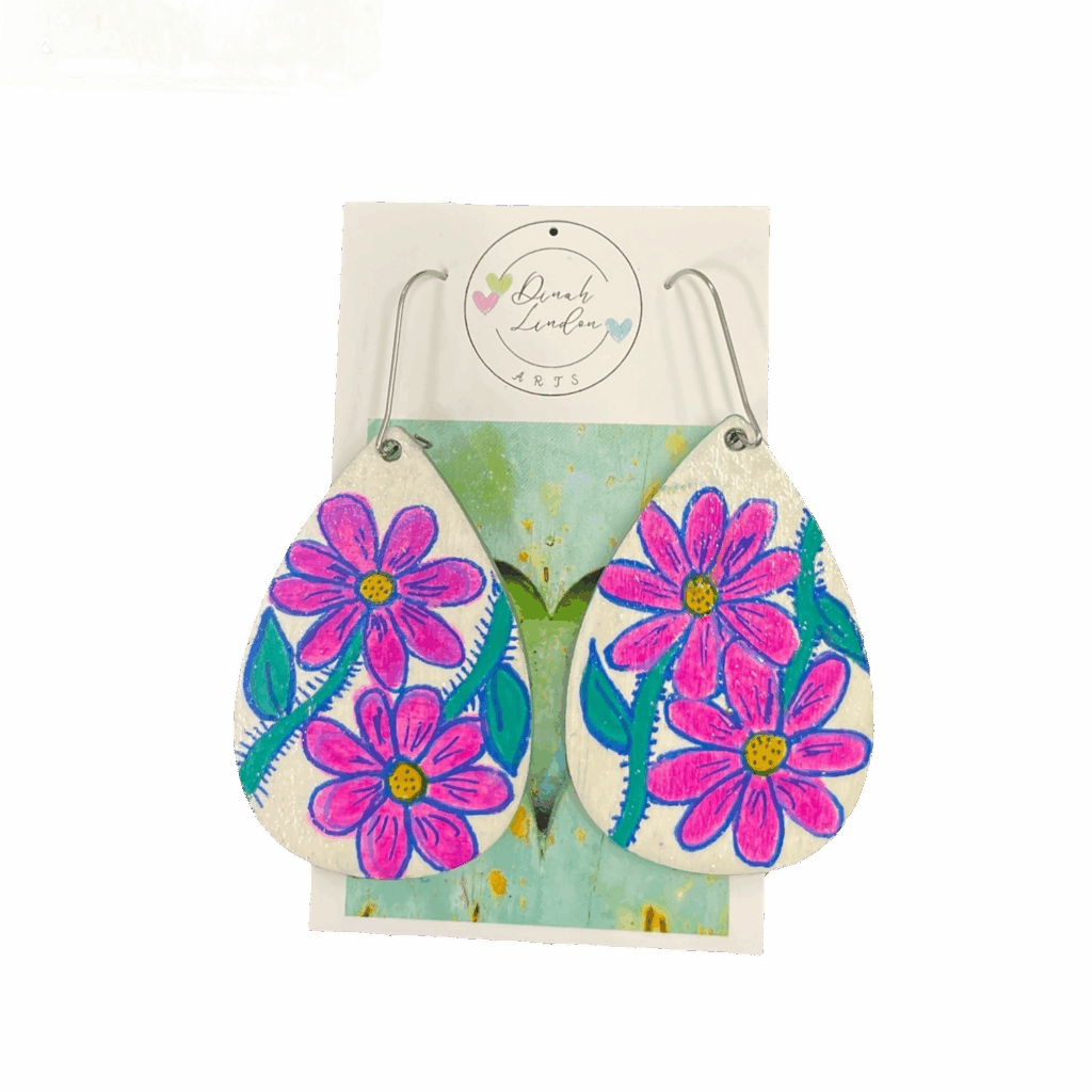 Cosmic Daisy Drops – bright teardrop earrings with pink daisies and green stems on a glossy white background by Dinah Lindon.