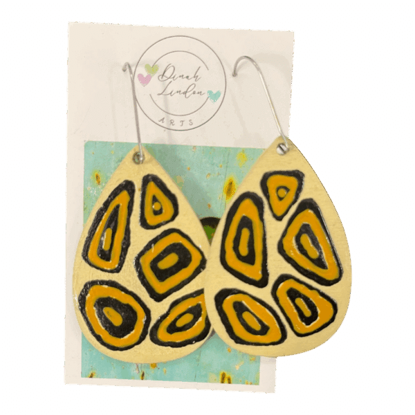 Savannah Signal Drops – golden tribal-style teardrop earrings with bold black shapes on a cream background.